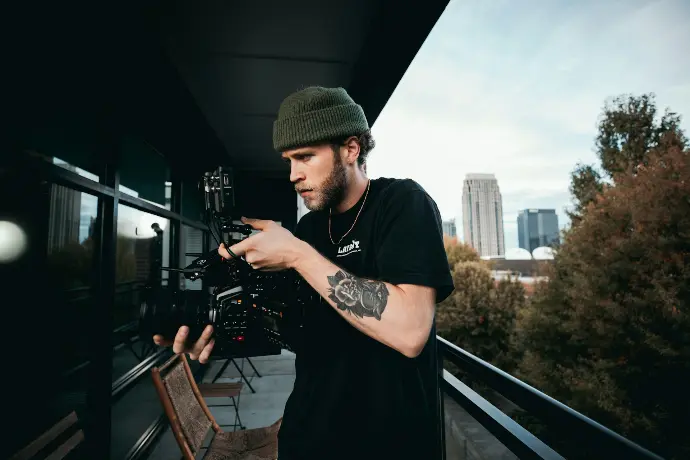 man in black crew neck t-shirt and black knit cap holding black smartphone